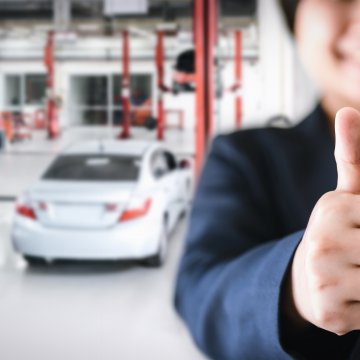 Thumbs up with car in background